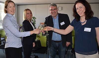 4 people raising their glasses and smiling into the camera